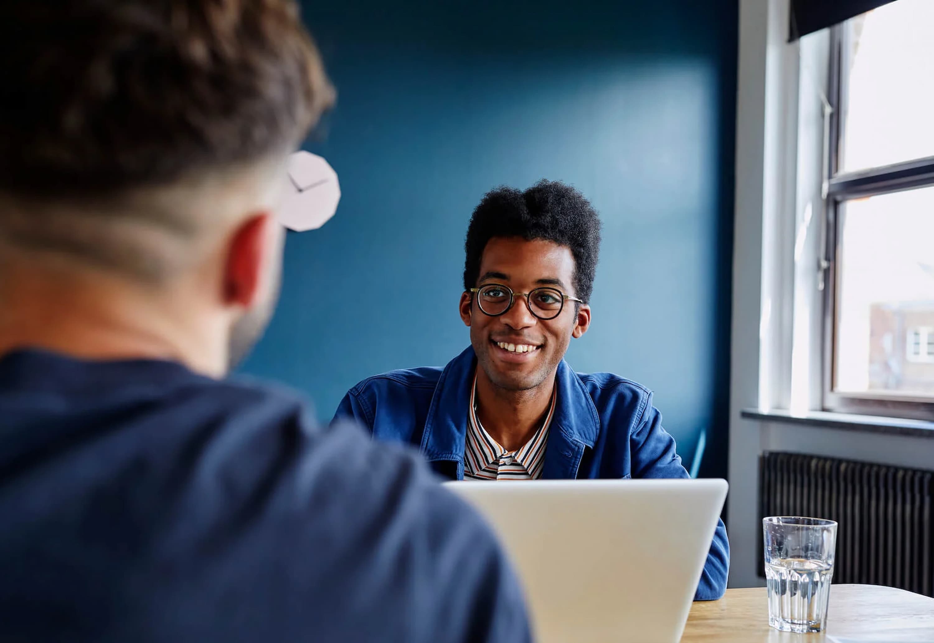 a-person-on-a-laptop-smiling-at-someone-across-the-table-learning-how-to-work-on-self-improvement