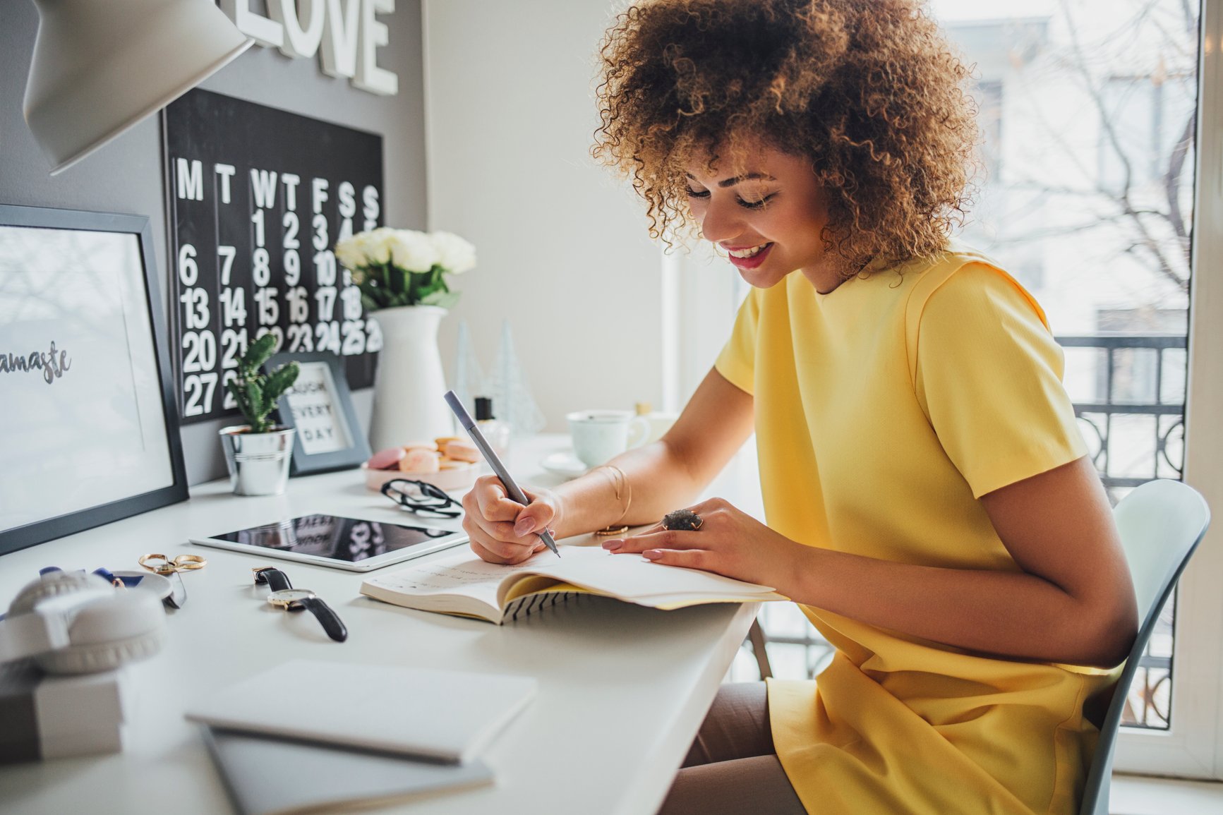 Black-woman-sitting-at-her-desk-writing-in-her-notebook-work-goal-examples