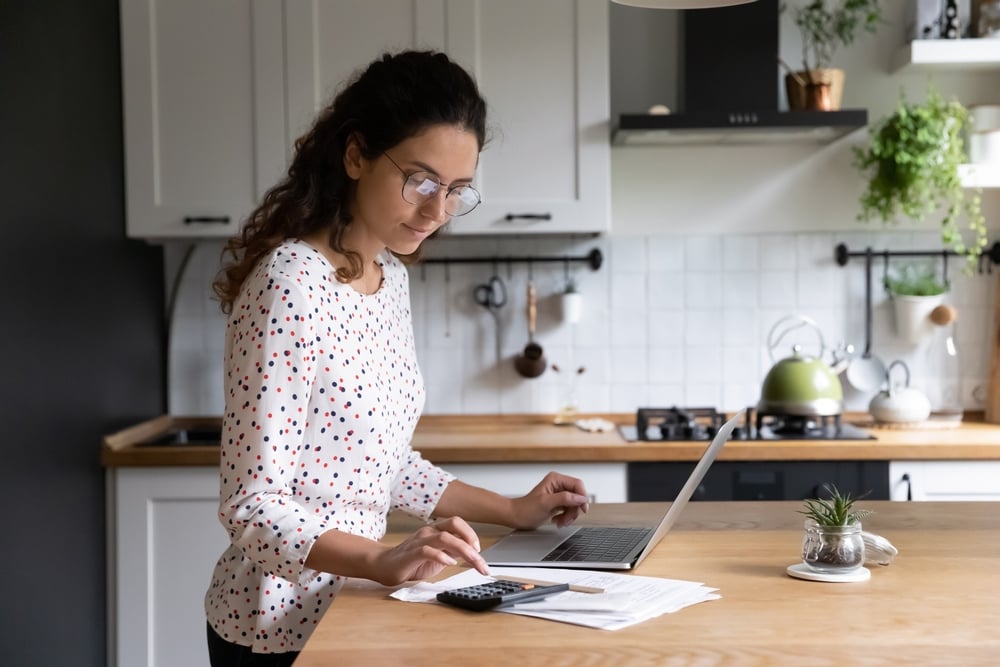 Female-standing-in-home-kitchen-doing-accounting-hard-work-vs-smart-work