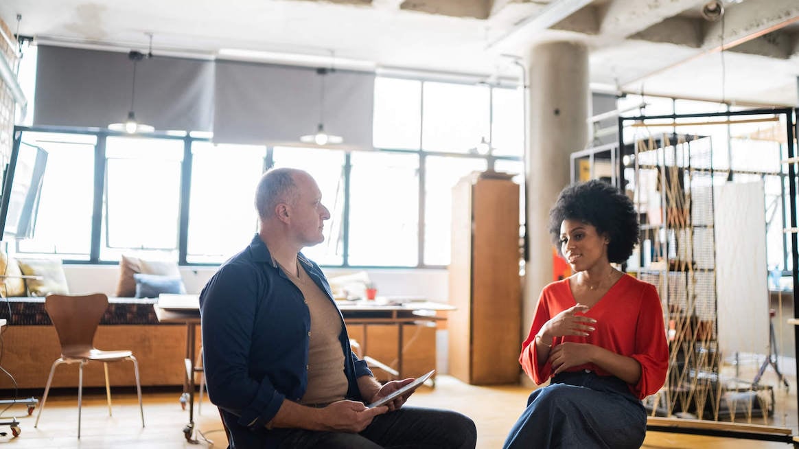 how-to-give-feedback-two-colleagues-talking-in-office