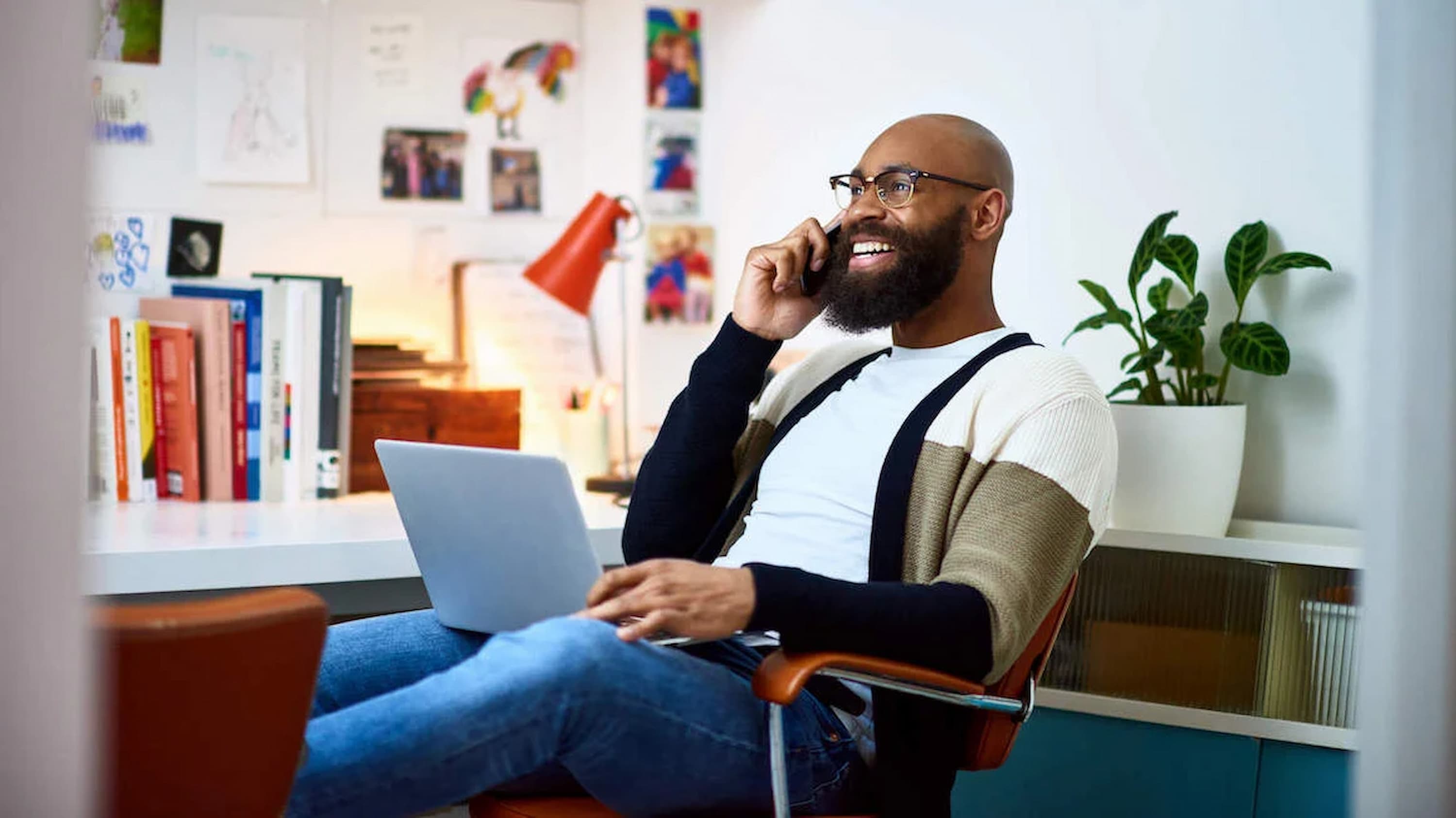 man-on-phone-laughing-at-desk-with-laptop-talking-about-self-efficacy