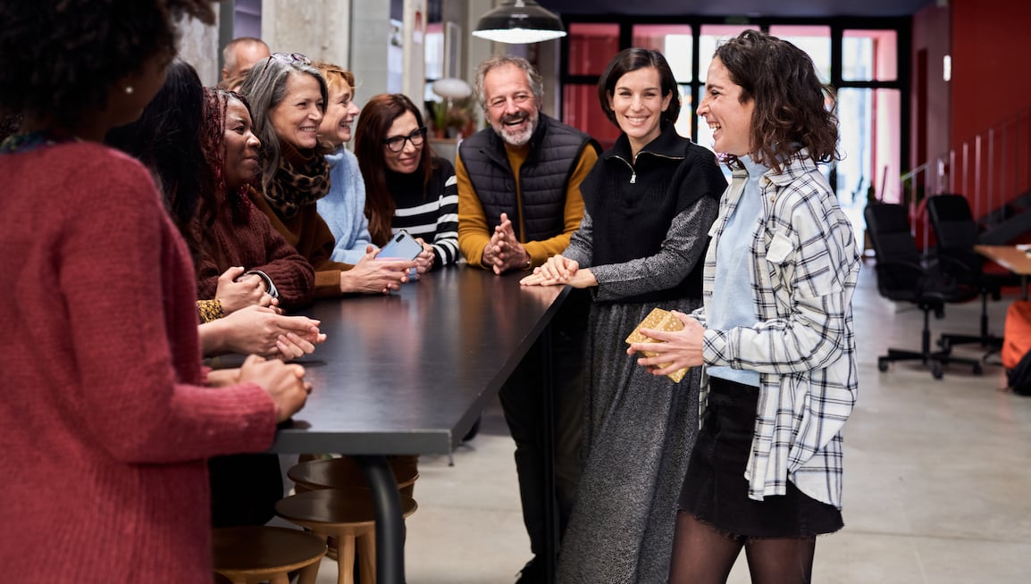 group-of-coworkers-laughing-aroundtable-managers-individual-contributors-experience-belonging-differently