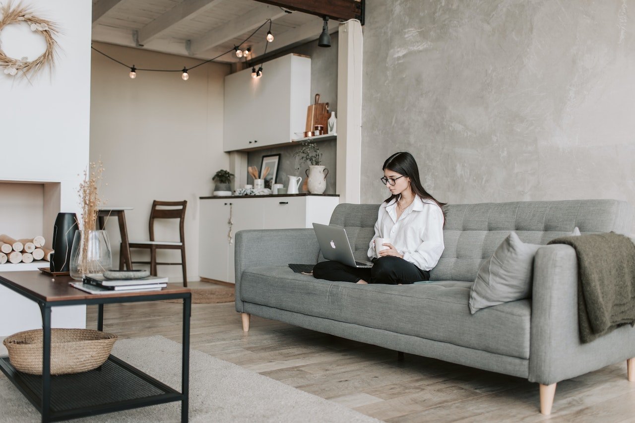 woman-at-a-clean-minimalist-house-sitting-on-couch-working-on-laptop-minimalist-lifestyle