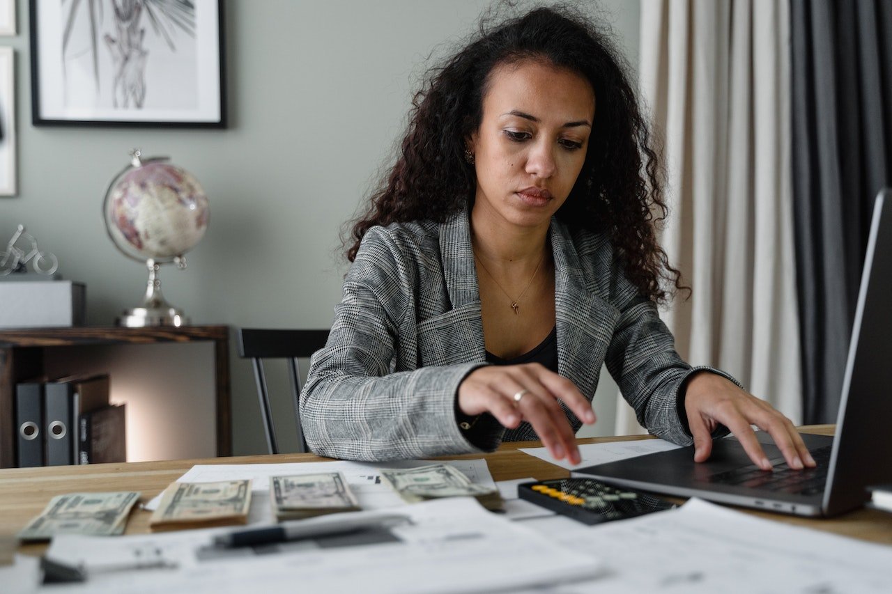 woman-counting-bills-with-calculator-and-using-laptop-entrepreneurial-skills